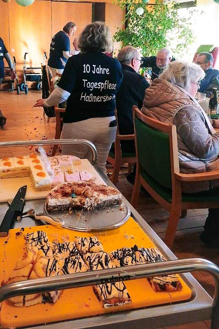 Kaffe und Kuchen beim Jubiläum der Tagespflege Servierwagen mit verschiedenen Kuchen im Hintergrund Kaffeegäste.