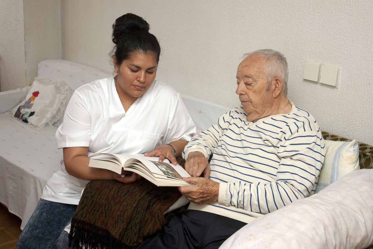 Pflegekarft erläutert einem Senior anhand von Unterlagen.