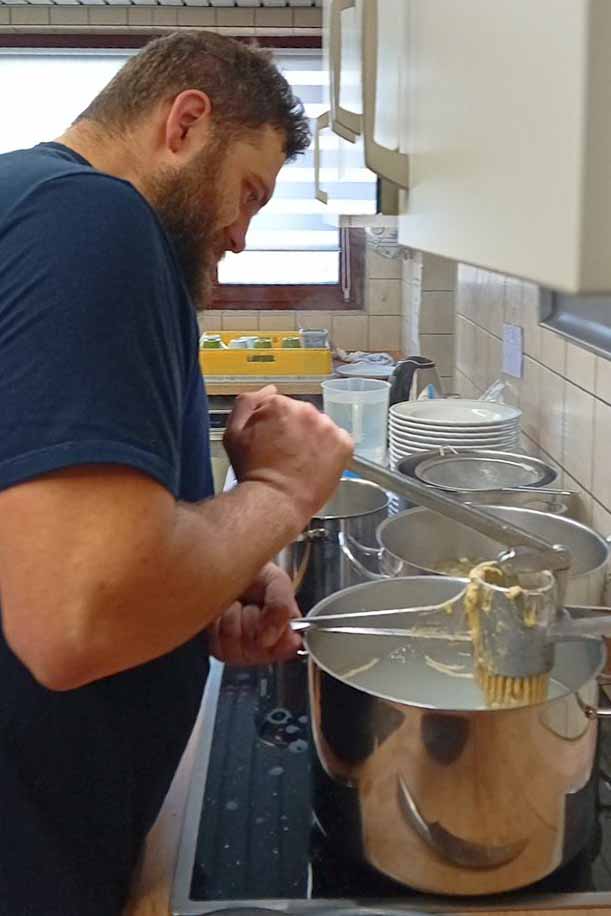 Handgemachte Spätzle und Burgunderbraten zum Jubiläum. Spätzle werden in einen Topf gepresst.